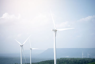 Wind turbines on field against sky