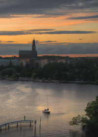 Scenic view of river by buildings against sky during sunset. högalid church and södermalm, stockholm 