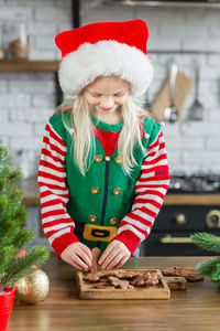 Girl in santa hat cooking, decorating gingerbread cookies