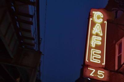 Low angle view of illuminated sign against clear sky at night