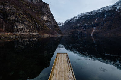 Scenic view along a jetty of a lake by mountain against sky