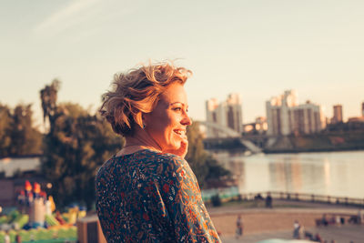 Young woman looking away and smiling during sunset