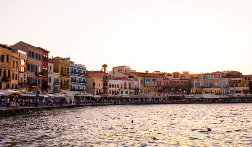 Buildings by river against clear sky in city