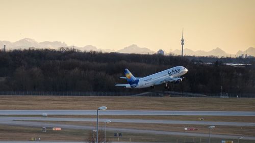 Airplane flying over airport runway against sky