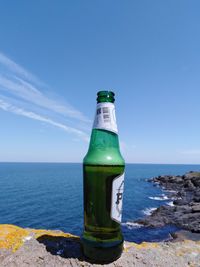 Water bottle on beach by sea against sky