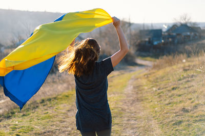 Woman holding a yellow and blue flag of ukraine in outdoors