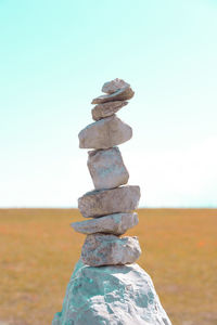 Stack of stones in sea against clear sky