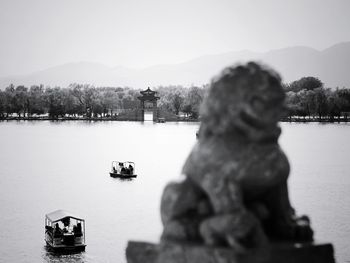 Statue by lake against clear sky