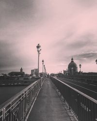 View of bridge over street against cloudy sky