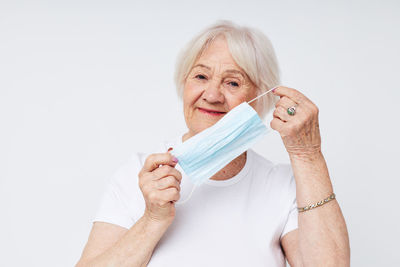 Close-up of woman holding dentures against white background