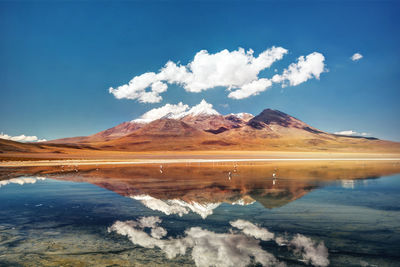 Scenic view of lake and mountains against blue sky