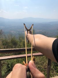 Midsection of person holding umbrella against mountain