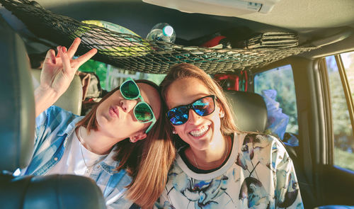Portrait of happy friends wearing sunglasses while sitting in car