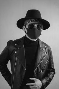 Midsection of man wearing hat standing against gray background