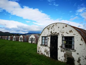 Old building by field against sky