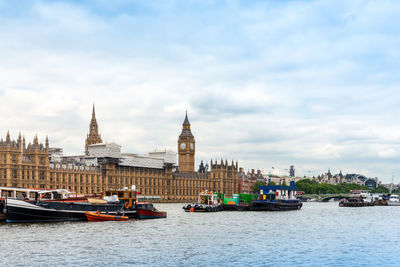 Boats sailing in river with city in background