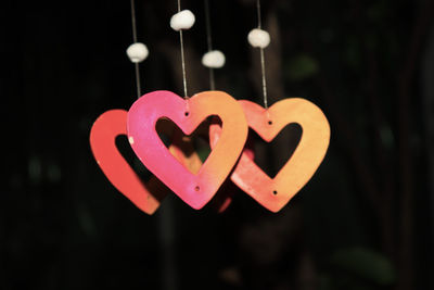 Close-up of heart shape hanging on pink light