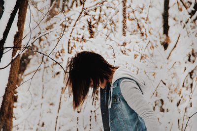 Woman standing by tree during winter