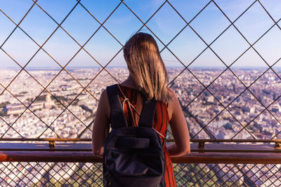 Rear view of woman standing by railing against sky