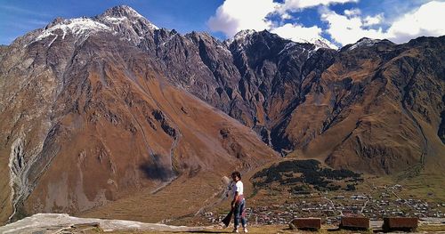 Tourists on mountain against cloudy sky