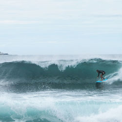 Man surfing in sea against sky