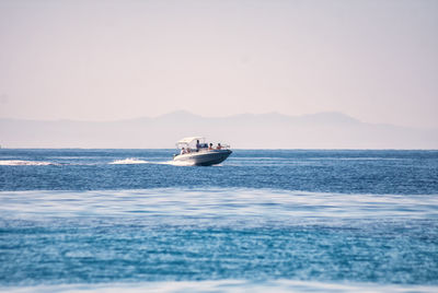 Boat sailing on sea against clear sky