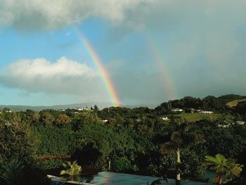 Scenic view of rainbow over trees against sky