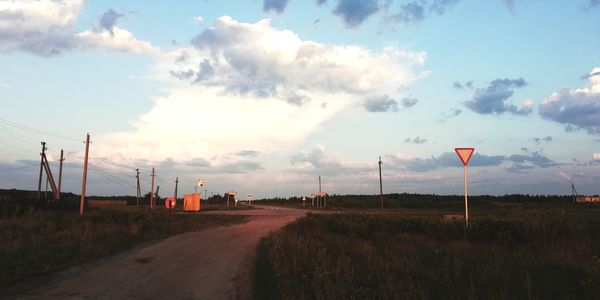 Road amidst field against sky