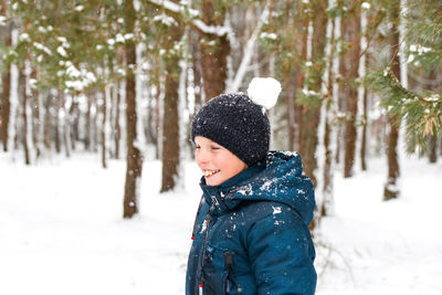 Rear view of boy standing on snow covered field