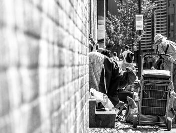 People relaxing on street against wall