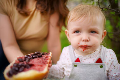 Mother and daughter eat jam bread at a picnic spring