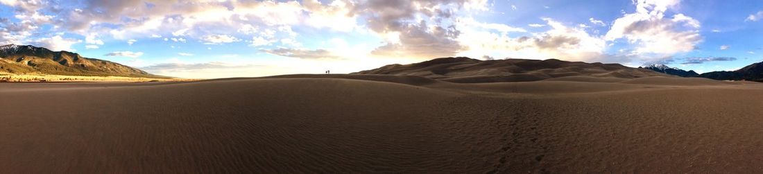 Panoramic view of desert against cloudy sky