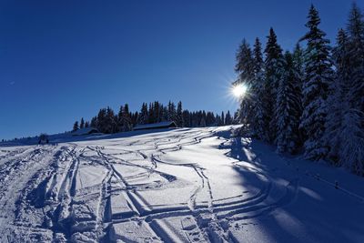 Snow covered field against clear blue sky