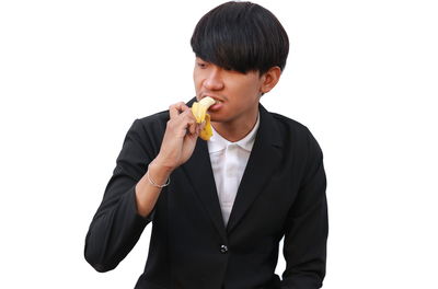 Young man eating food against white background