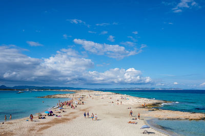 Panoramic view of people on beach against blue sky