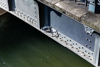 A pigeon sits on a girder of the bridge over a canal
