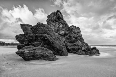 Rock formation on beach against sky