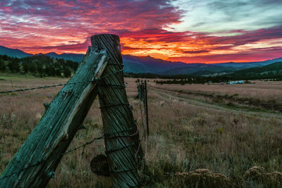 Wooden fence on field against sky during sunset