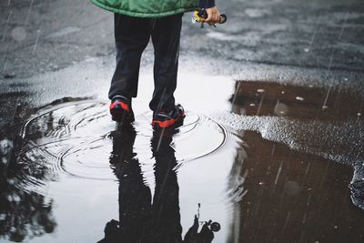 Low section of man standing on wet street