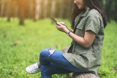 Side view of man using mobile phone in grass