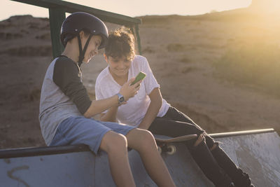 Couple of friends enjoying free time at the skatepark looking video online. teenagers having fun 