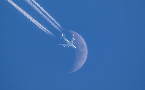 Low angle view of airplane flying against clear blue sky