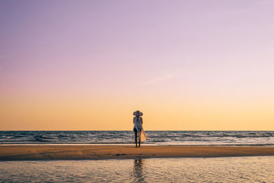 Man standing on beach against sky during sunset
