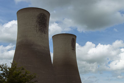 Two grey, industrial power station cooling towers and blue sky clouds