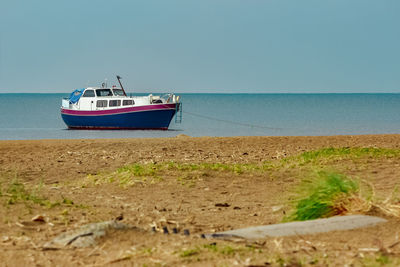 Boat moored on beach against clear sky