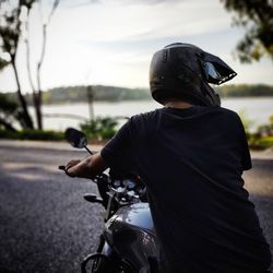 Rear view of man riding motorcycle on road