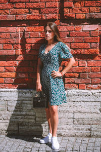 Portrait of smiling woman standing against brick wall