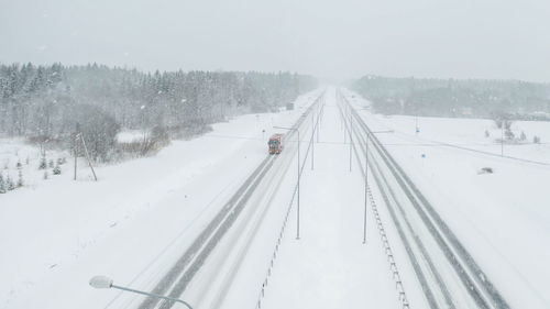 Snow covered road amidst trees during winter