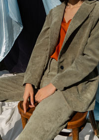 Midsection of young woman sitting on wooden chair at event