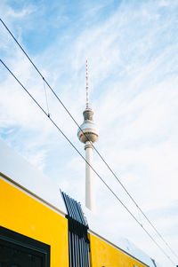 Low angle view of communications tower against cloudy sky